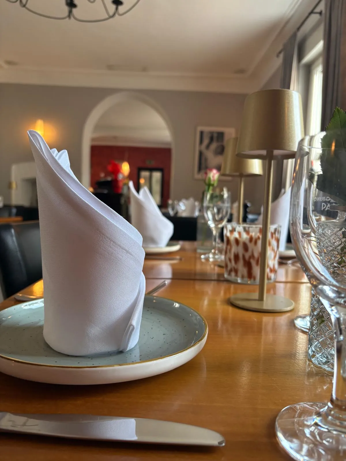 Elegant gedeckter Tisch im Gourmet-Restaurant mit kunstvoll gefalteter weißer Serviette auf einem modernen Teller.