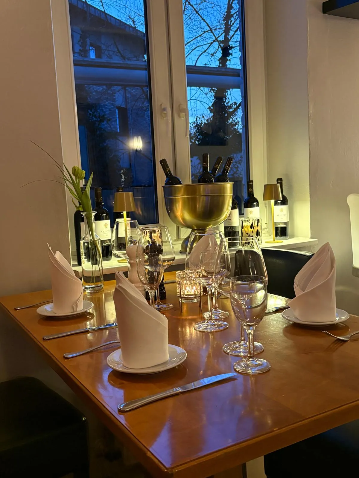 Festlich gedeckter Tisch für ein Abendessen im Restaurant mit Weinkühler und stilvoller Dekoration.