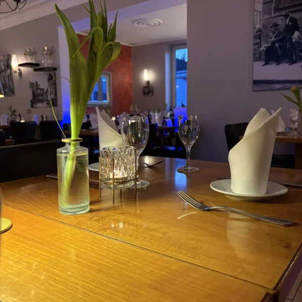 Elegant gedeckter Tisch im Restaurant Vittoria mit Kerzenschein, Weingläsern und einer frischen Tulpe.