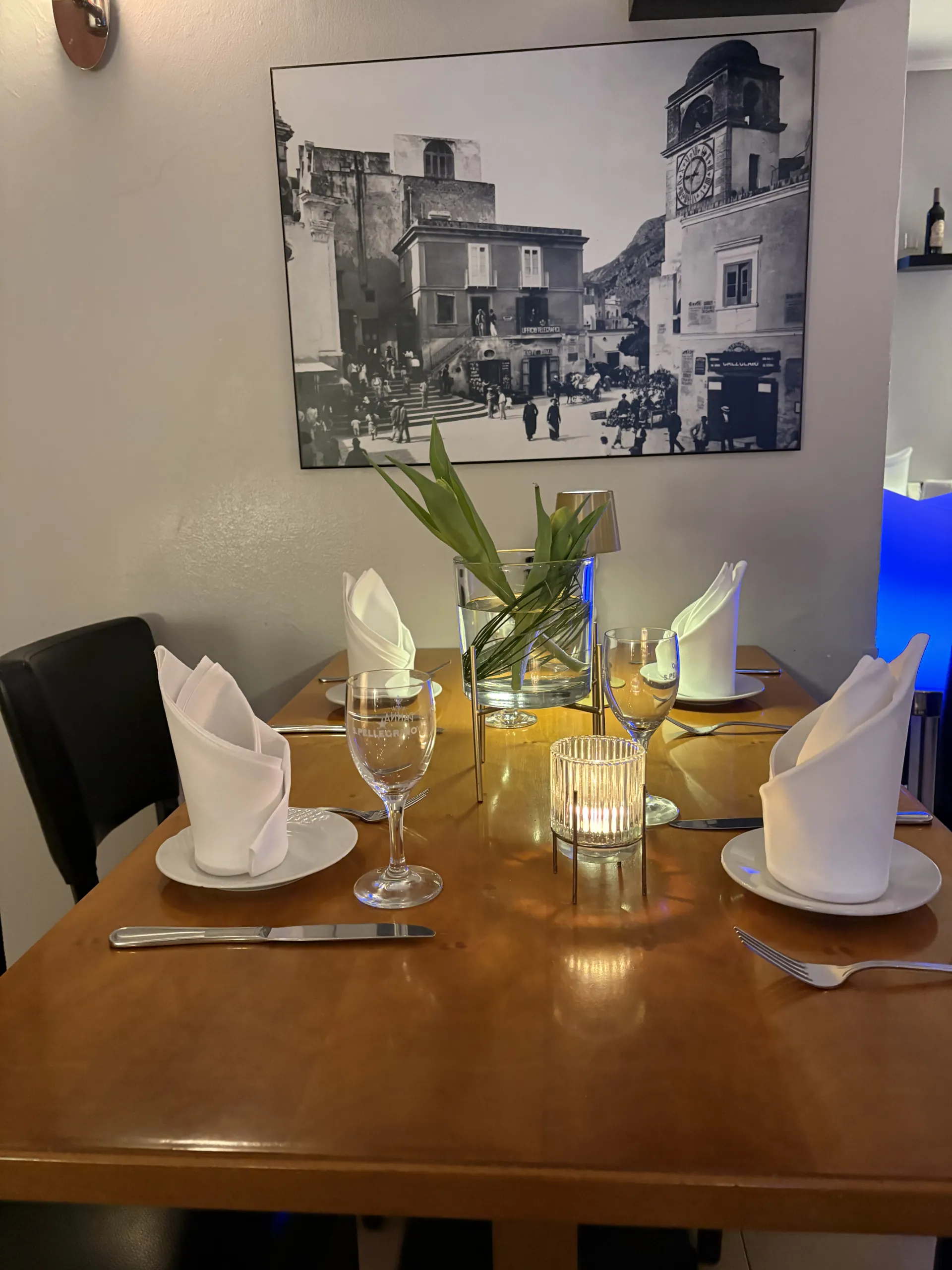 Elegant gedeckter Tisch im Restaurant Vittoria mit weißen Stoffservietten und mediterranem Wandschmuck.