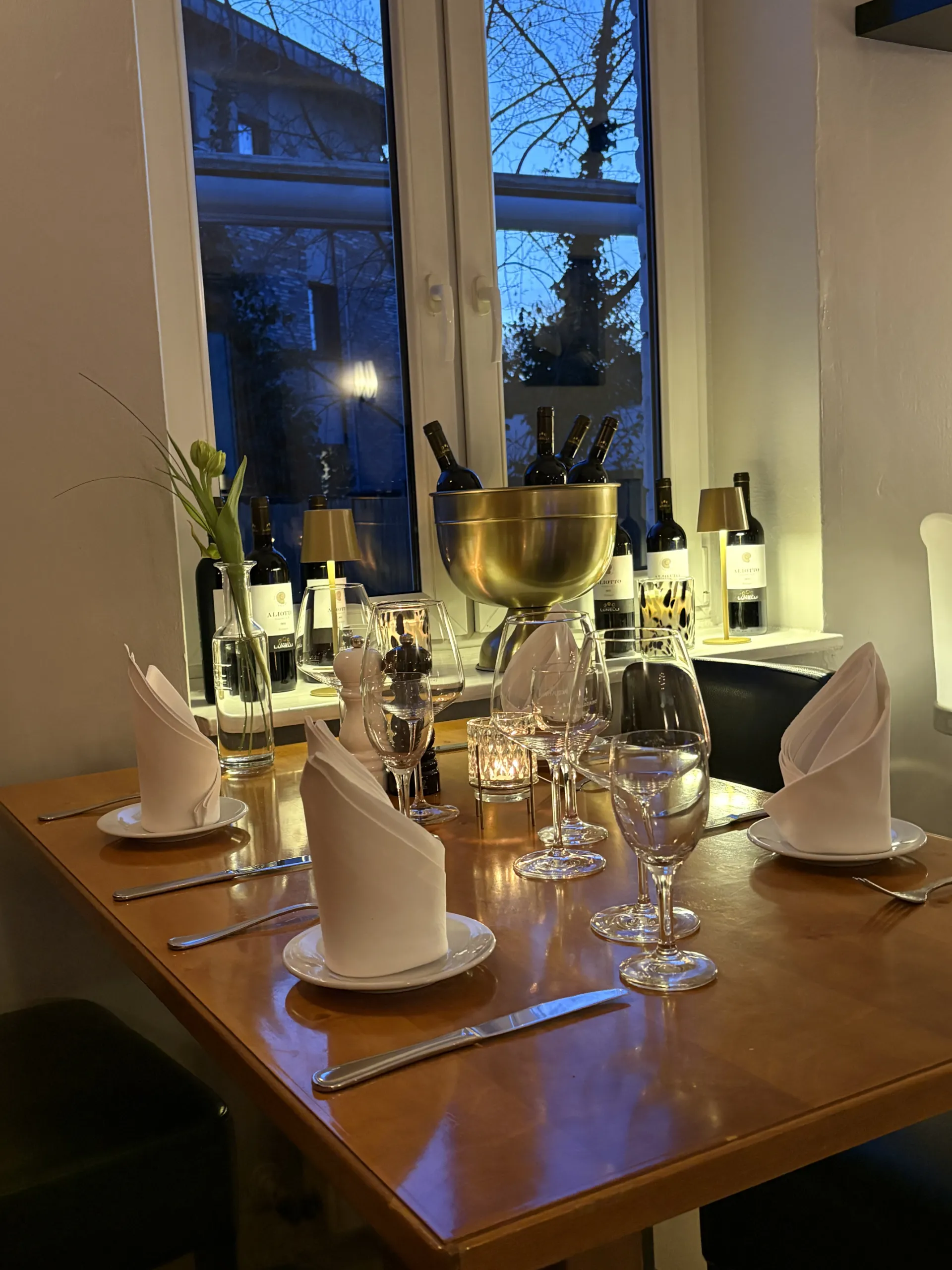 Elegant gedeckter Tisch im Restaurant Vittoria mit Weingläsern und Weinkühler für ein mediterranes Erlebnis.